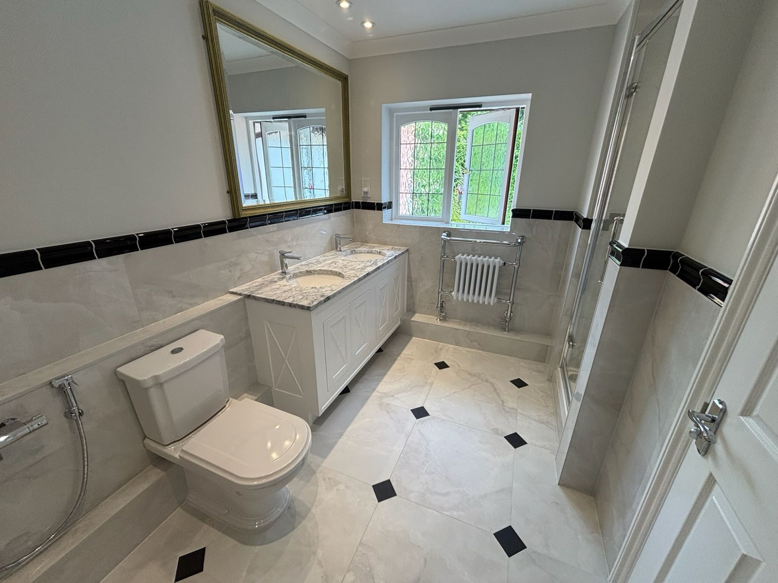 Classic marble-effect bathroom with double vanity, gold-framed mirror and diamond-inlay tiled floor