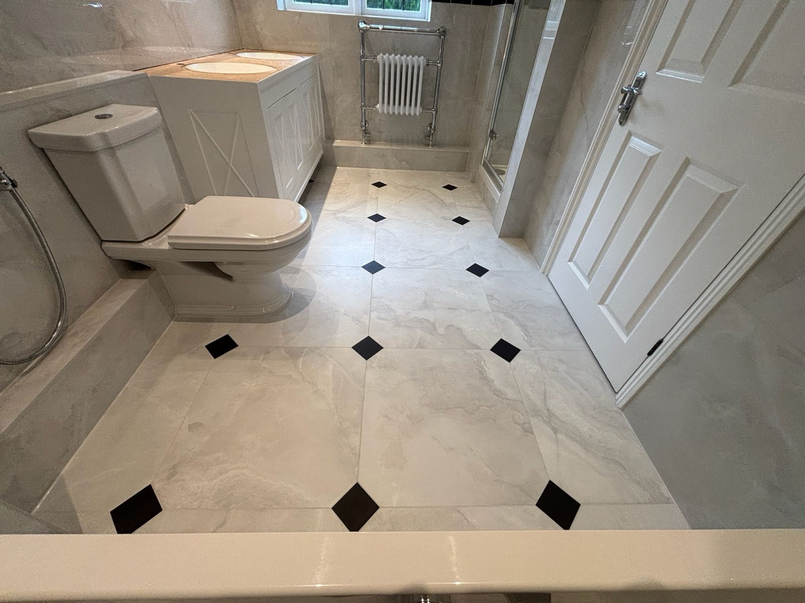 Marble-effect family bathroom with traditional WC, vanity unit, shower and diamond-inlay floor