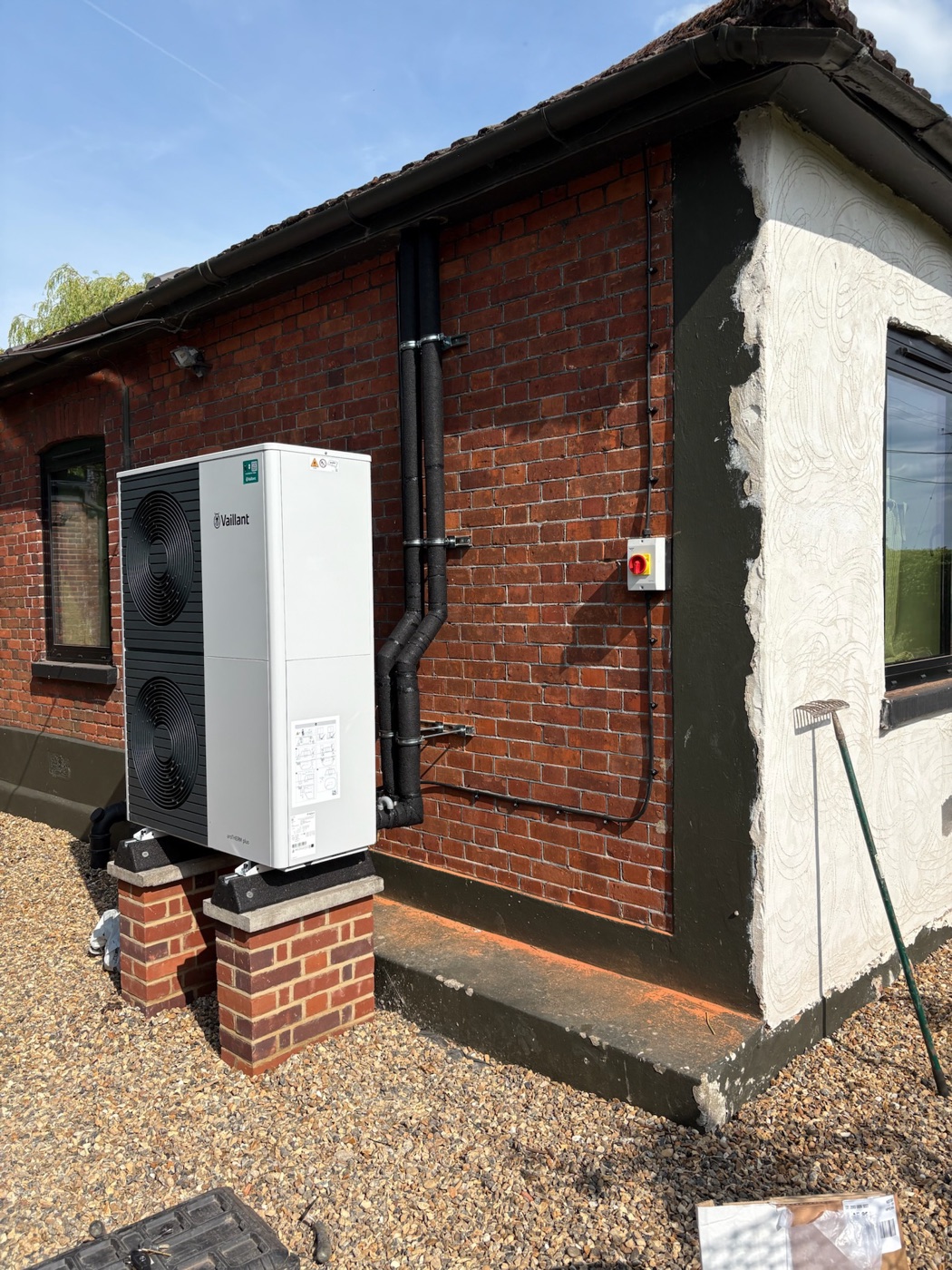 Vaillant air source heat pump on brick plinths against a rendered wall