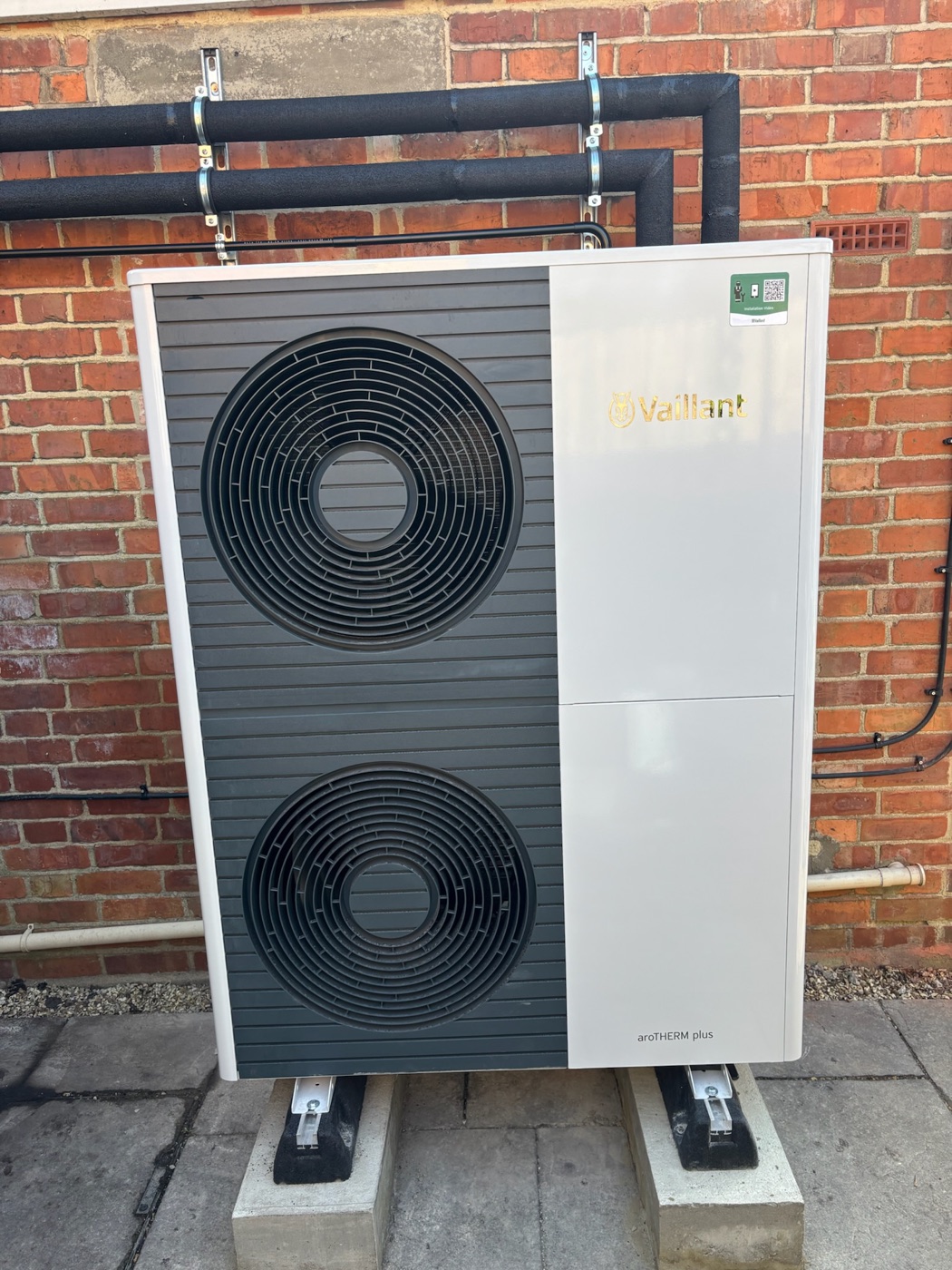 Vaillant aroTHERM plus air source heat pump installed against a brick wall